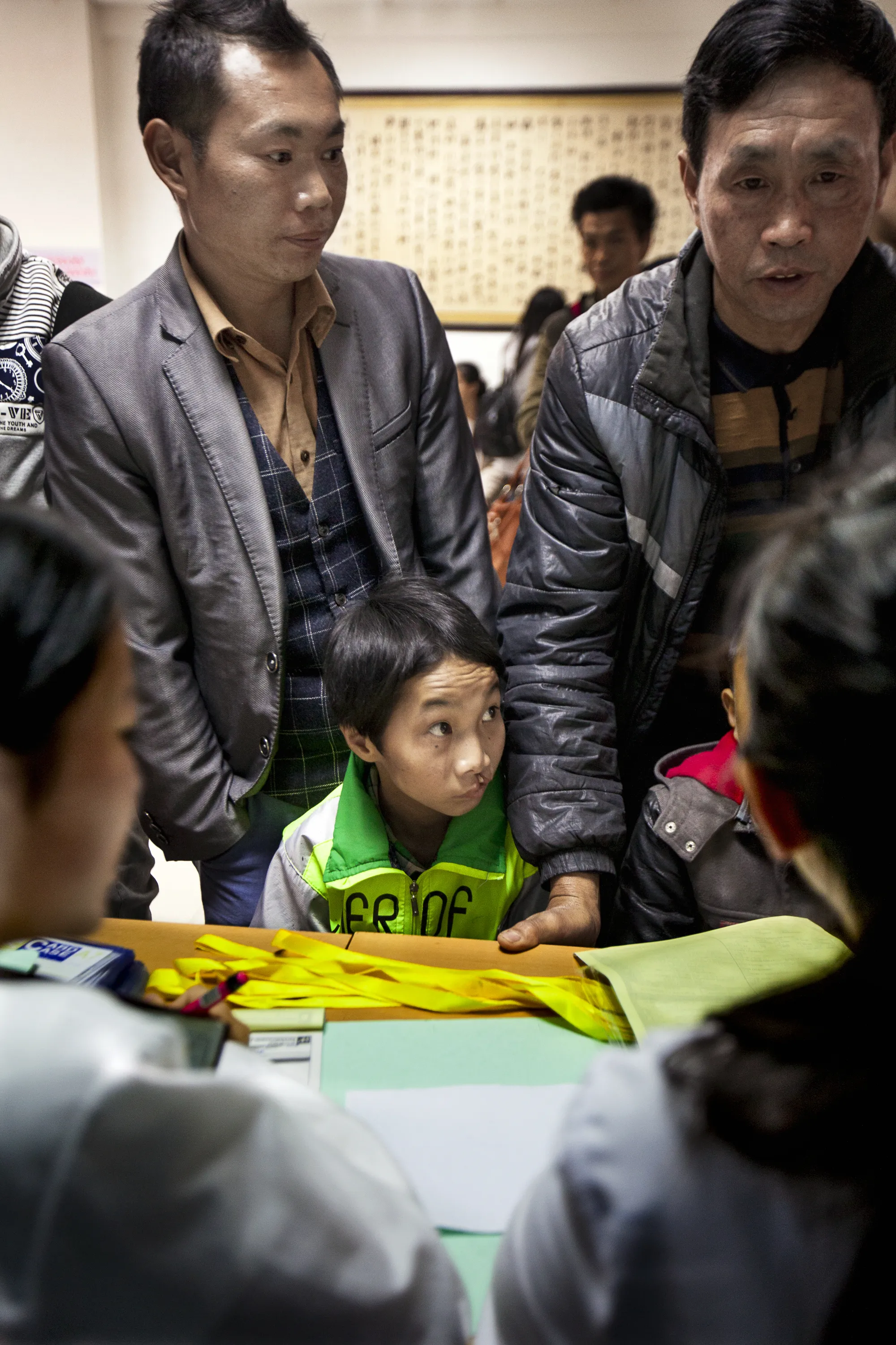 Paidong, left, registers Shijun for screening during a 2016 Operation Smile China surgical program in Dafang.