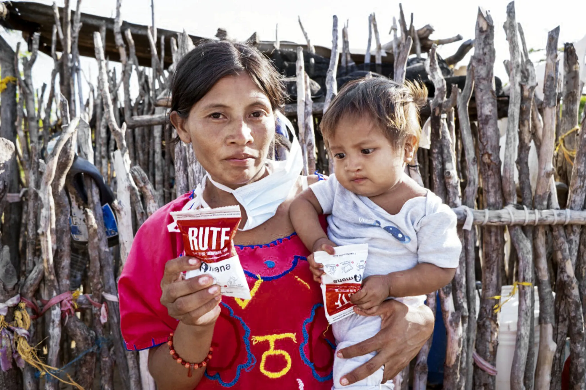 Patricia and her son, Wilmar, stand in their kitchen in La Guajira holding a package of ready-to-use therapeutic food.
