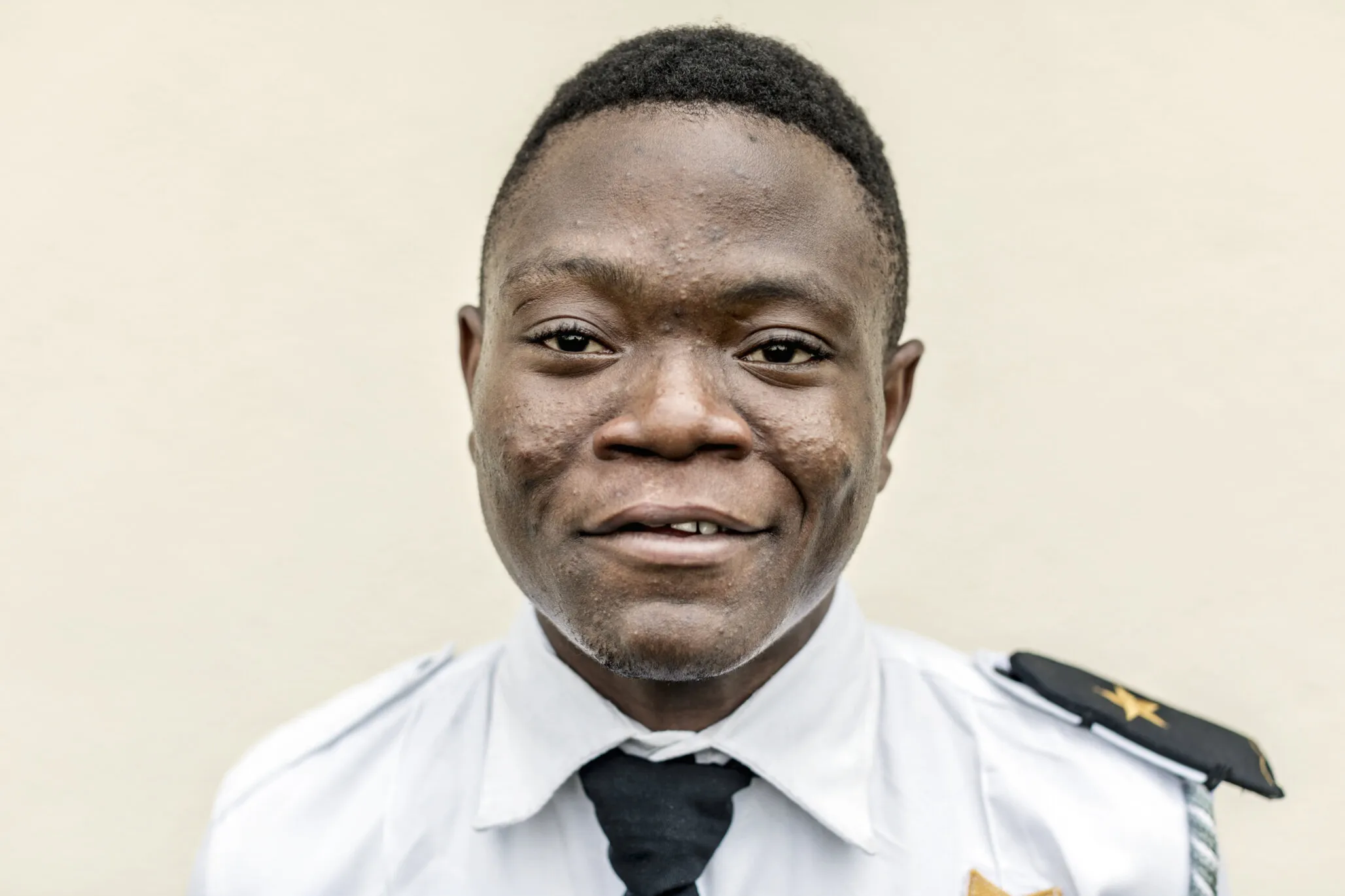 Samuel smiles proudly in his security guard uniform.