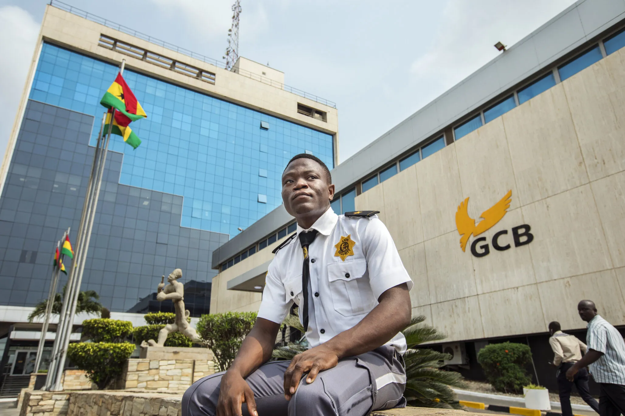 Samuel sits outside of the bank where he works as a security guard in Accra.