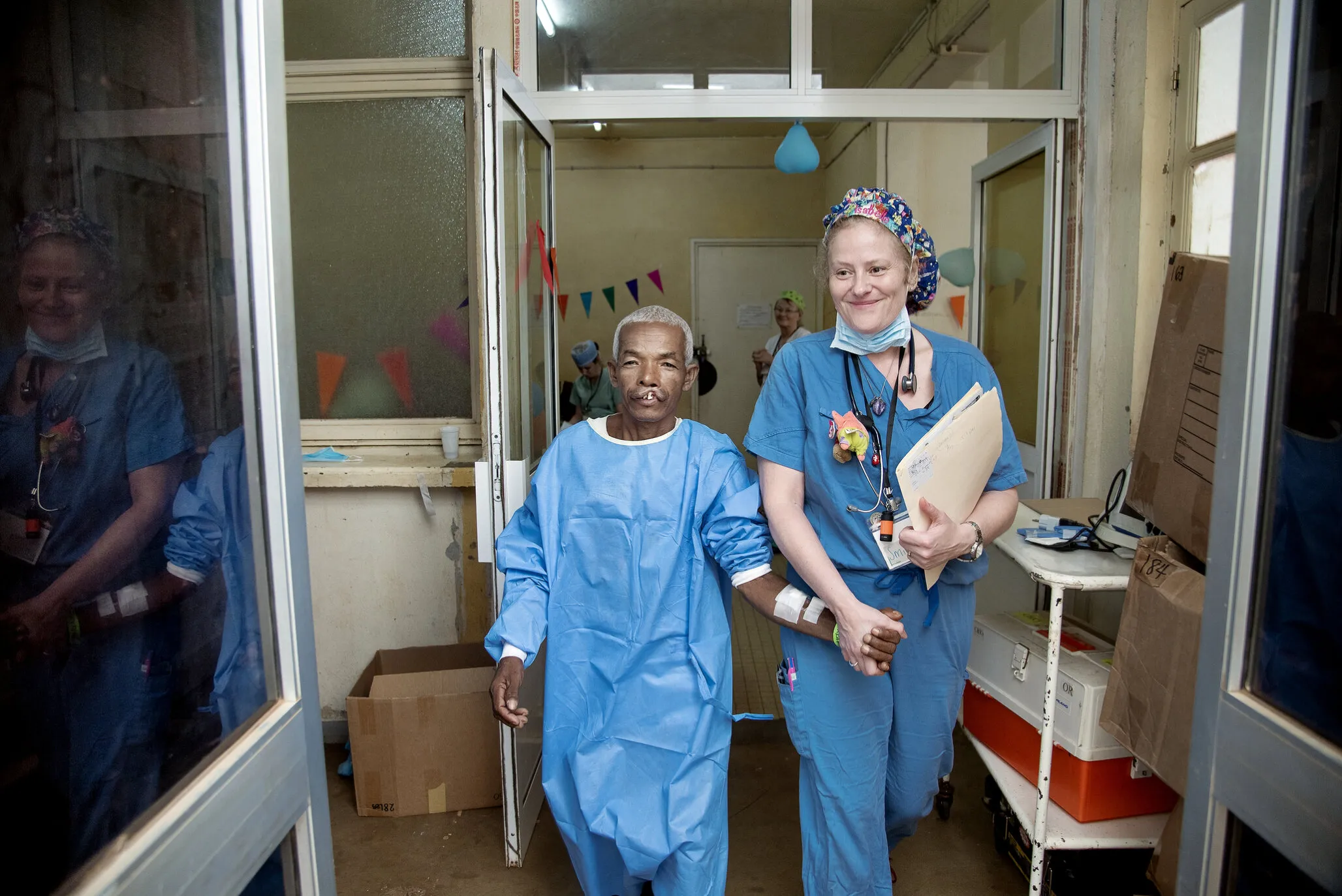 Alfred walks hand-in-hand into the operating room with post-anesthesia care unit physician Isabelle Simoneau of the U.S. during a 2018 Operation Smile surgical program in Antsirabe, Madagascar.
