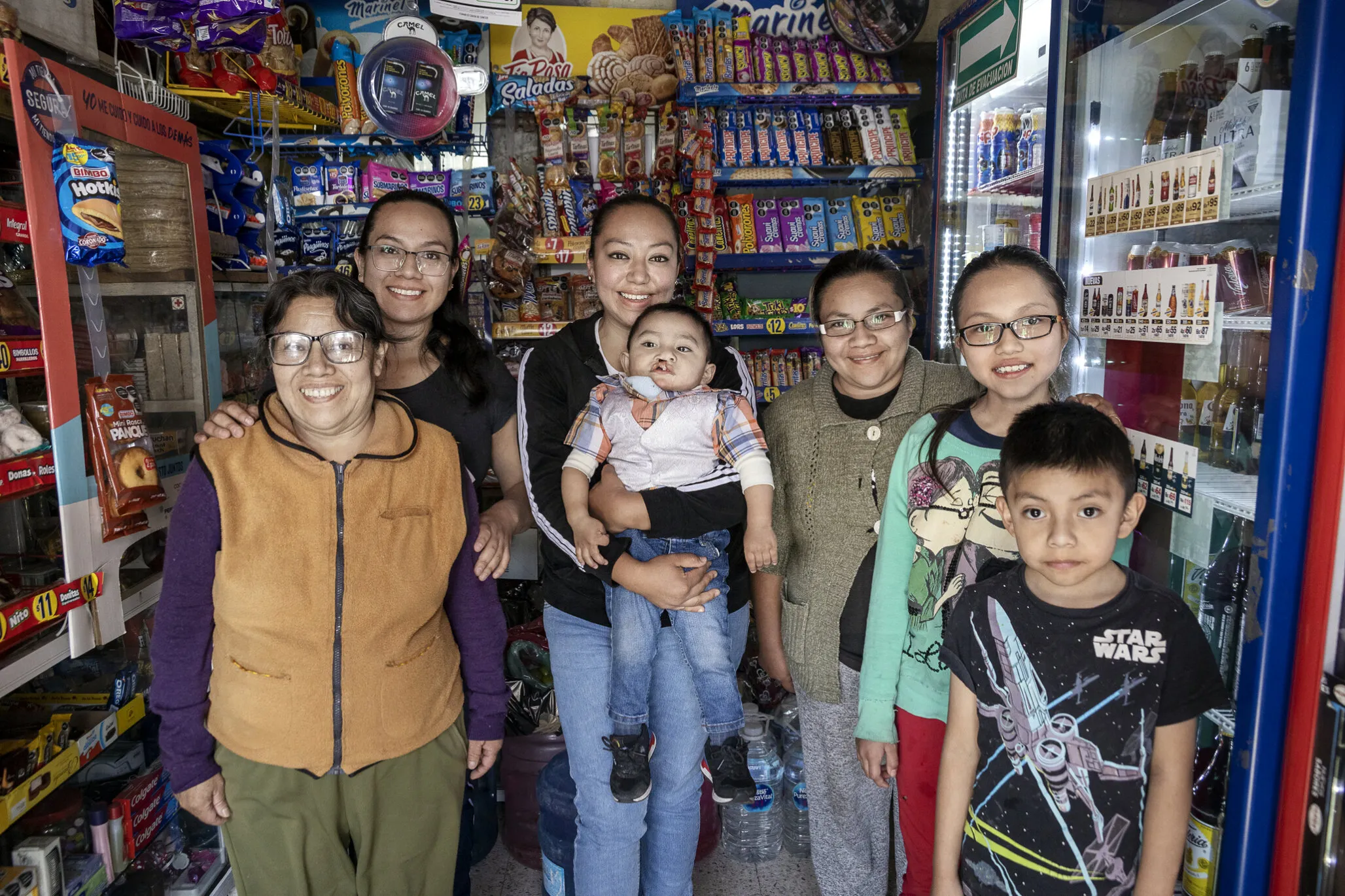 Sebastian is surrounded by his mom, María, and other members of his family as they pose for a picture inside his family’s store.