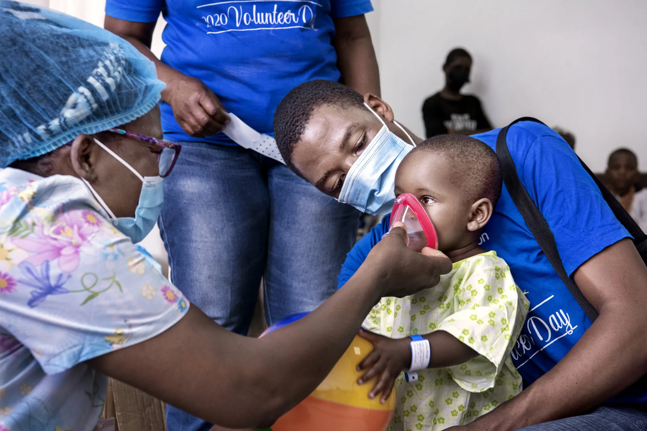 Cathy and pre- and post-operative nurse Donald Mlombwa of Malawi comfort Julita by showing her some of the surgical equipment she will see after entering the operating room for her cleft surgery.