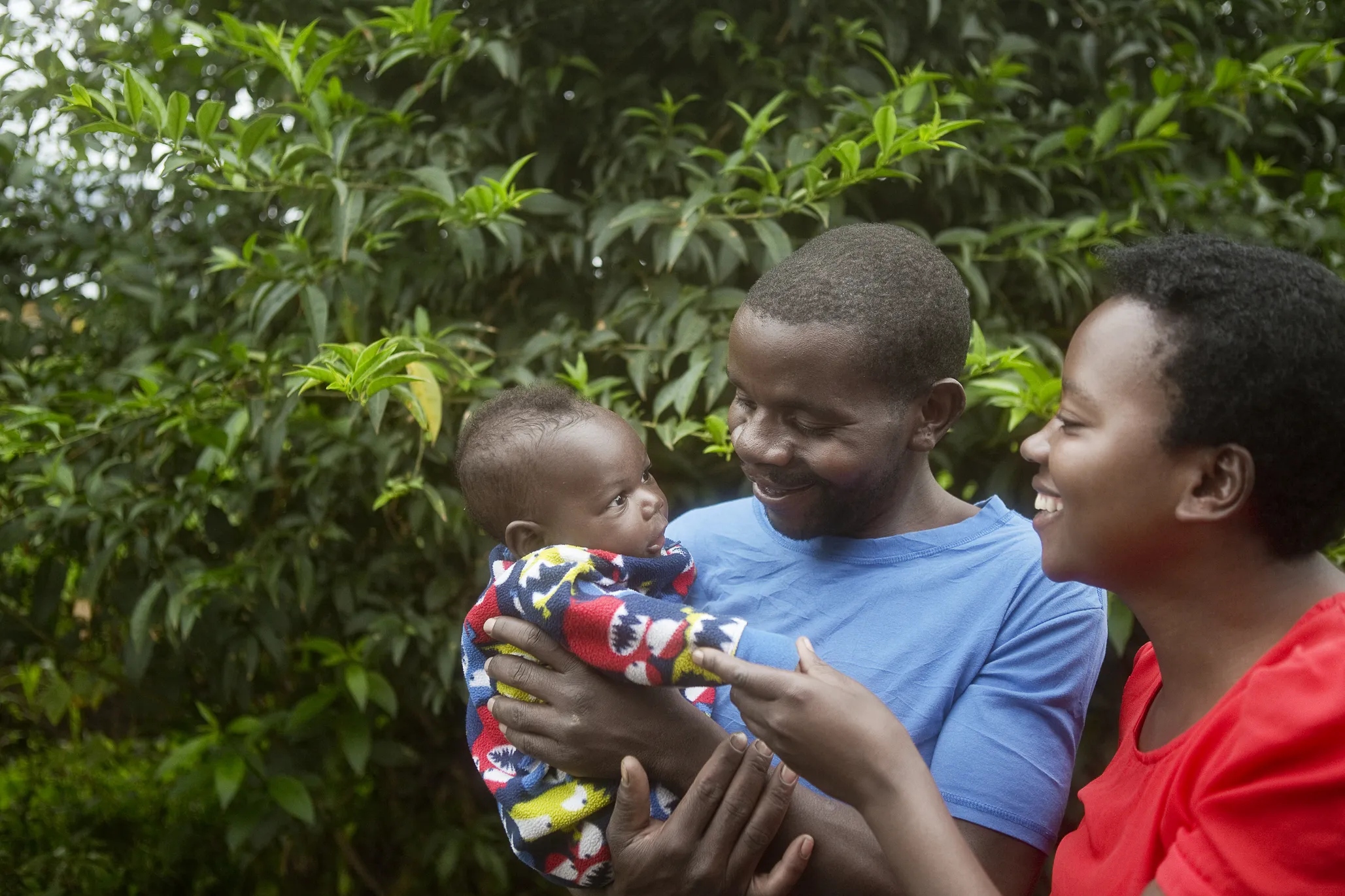 Enok and his wife smile widely at their child.