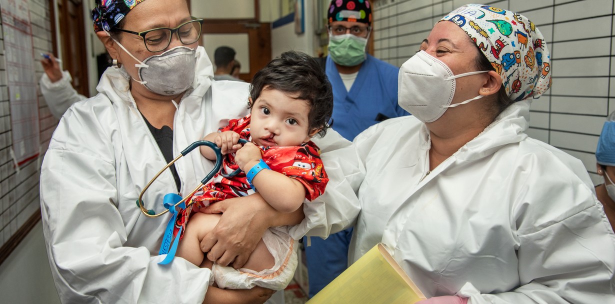 During a 2021 surgical program in Guatemala, 10-month-old Juan Elias is carried to the operating room by anesthesiologists Drs. Carla Garcia and Silvia Ramos.