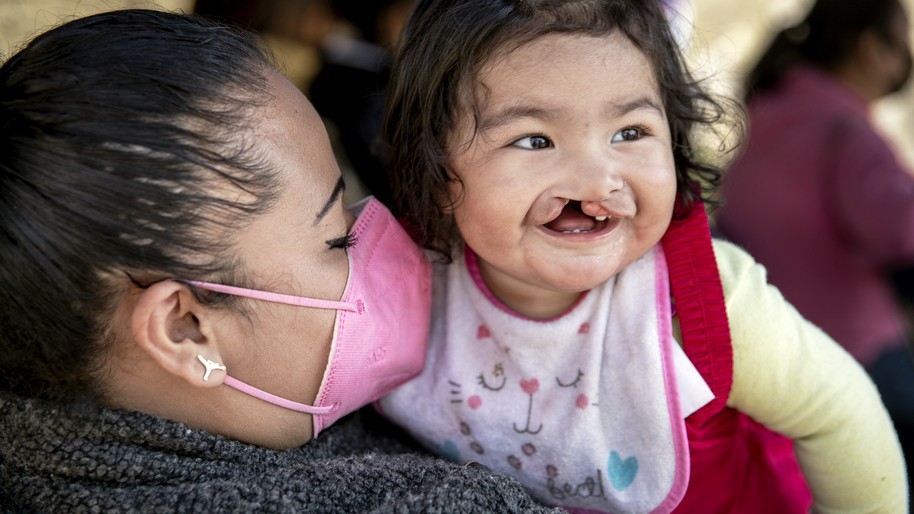 In Mexico, a mother holds her smiling child after a COVID-19 test