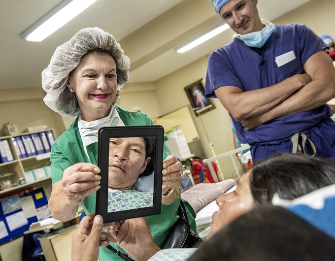 Andrea of Peru looks at her new smile for the first time in a mirror held by Linda Highfield, a volunteer clinical coordinator and nurse, of the United States. 