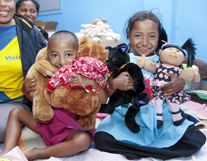 Four-year-old Clarra and 8-year-old Vololoniana hug teddy bears in child life during an Operation Smile surgical program in Antananarivo, Madagascar.