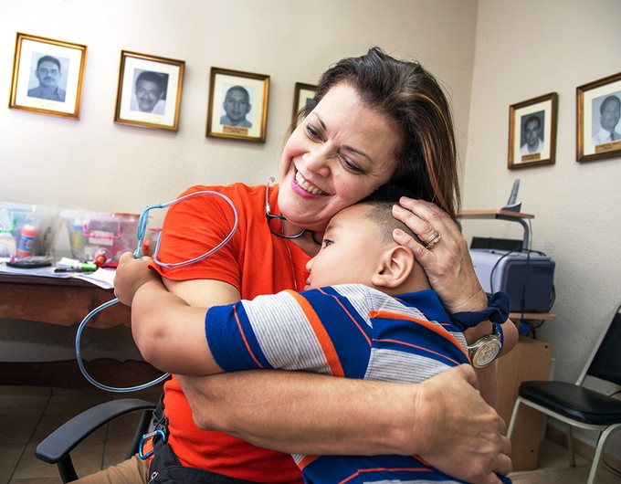 Wearing a red shirt, speech pathologist Gloria Vilches hugs 5-year-old Josue during a 2017 Operation Smile Honduras surgical program at San Felipe Hospital in Tegucigalpa. 