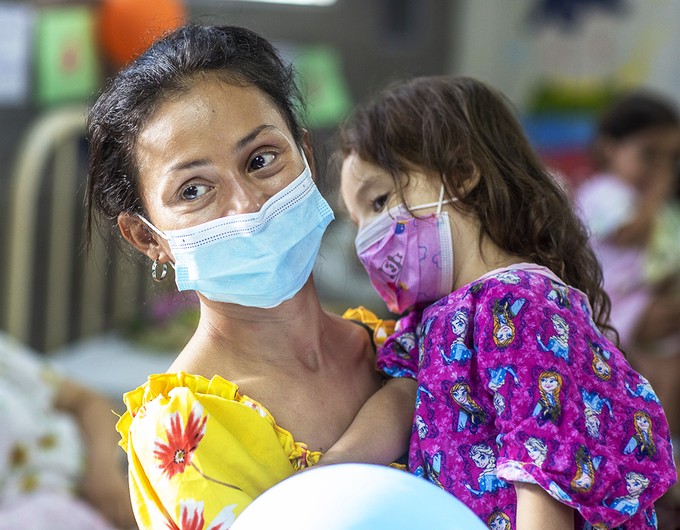 Ana, holds her daughter, Zoe, wearing masks in the pre-operative ward during an Operation Smile Honduras surgical program. 
