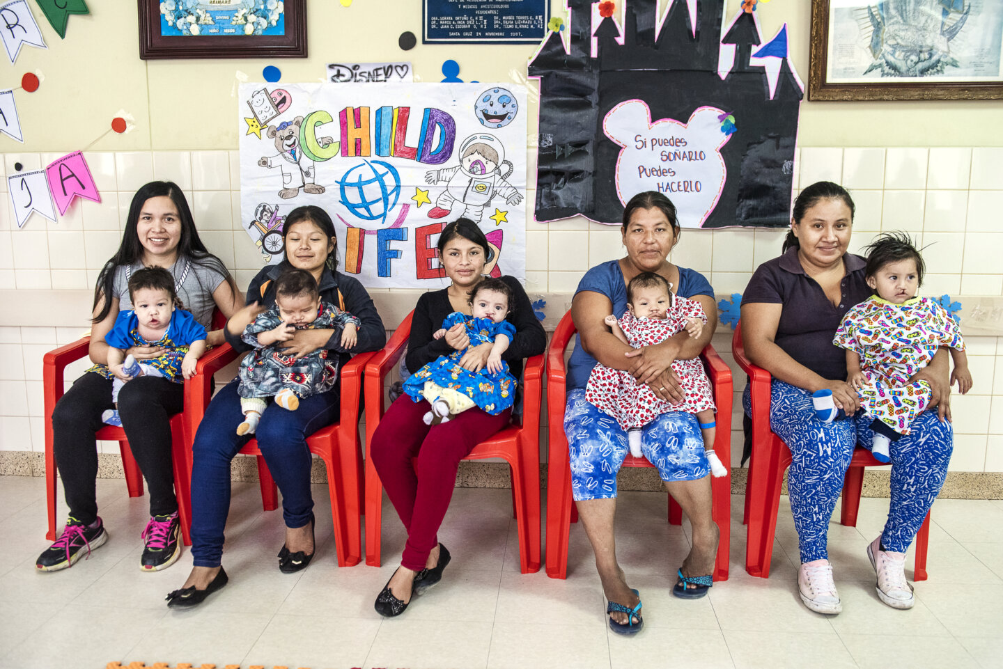 Jack and America, left, sit beside more mothers and patients who await to learn more from the Operation Smile Bolivia volunteer team during a 2018 surgical program.