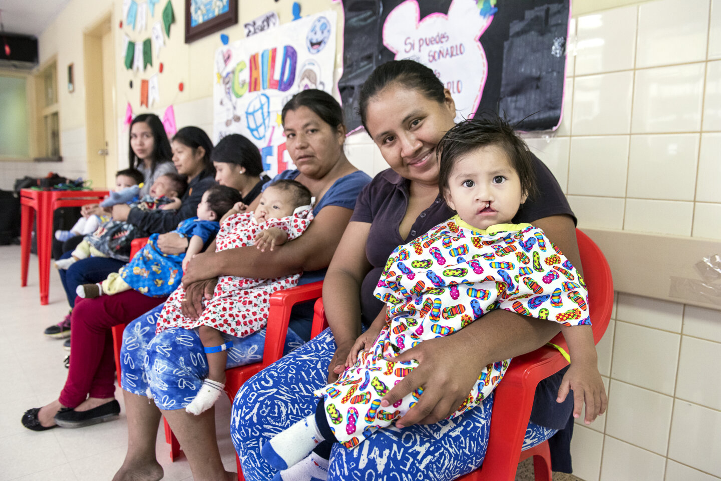 During a 2018 Operation Smile Bolivia surgical program, Nora and Damian, right, wait for care alongside four other patients and parents.