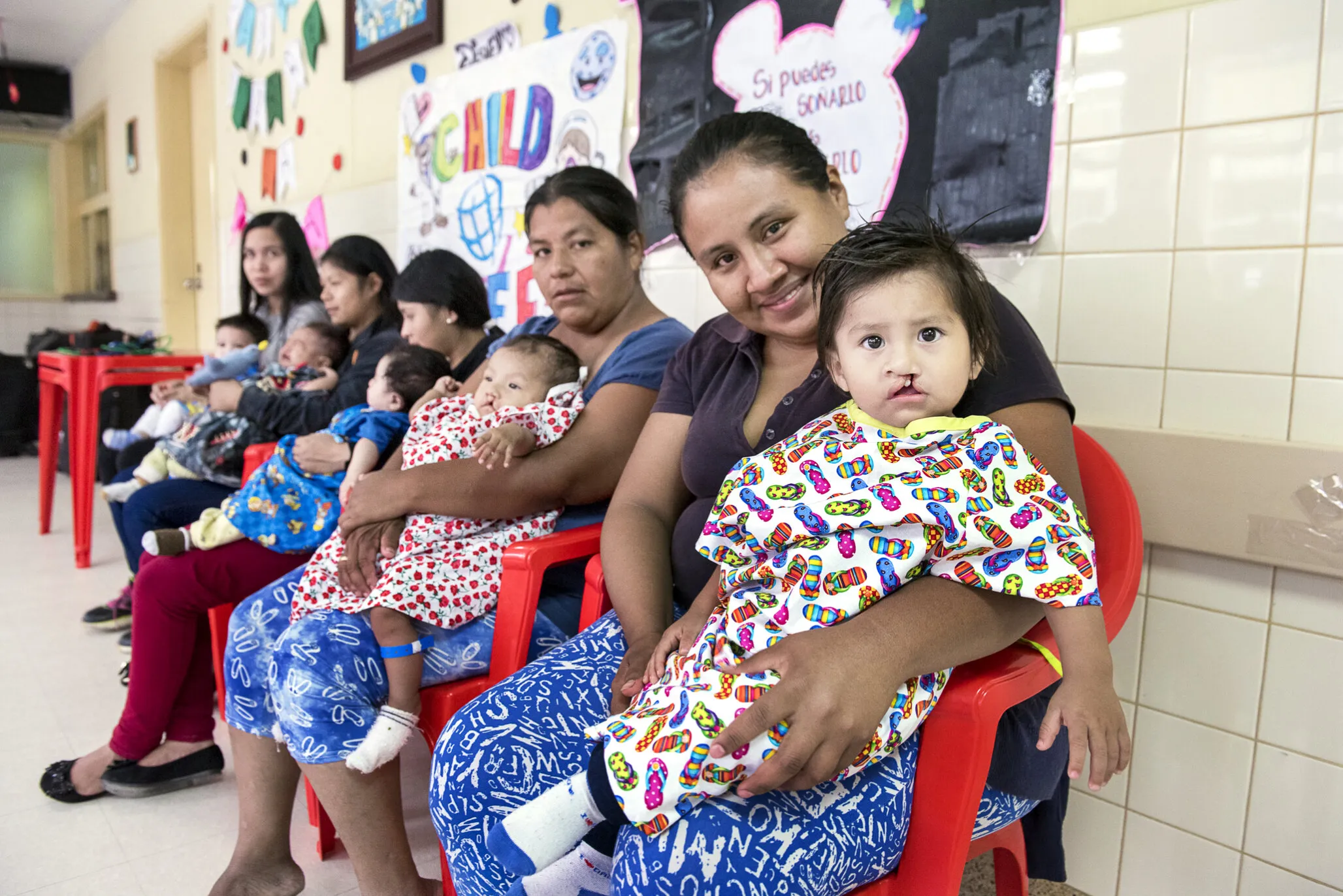 During a 2018 Operation Smile Bolivia surgical program, Nora and Damian, right, wait for care alongside four other patients and parents.