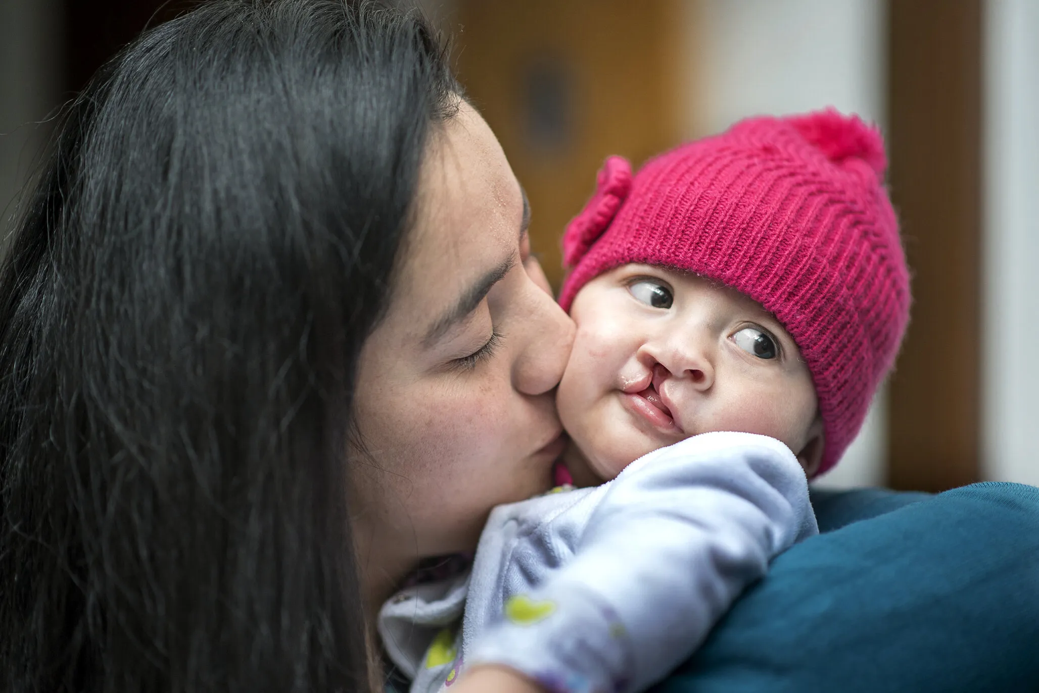 Luciana's mom gives her a kiss on the cheek.