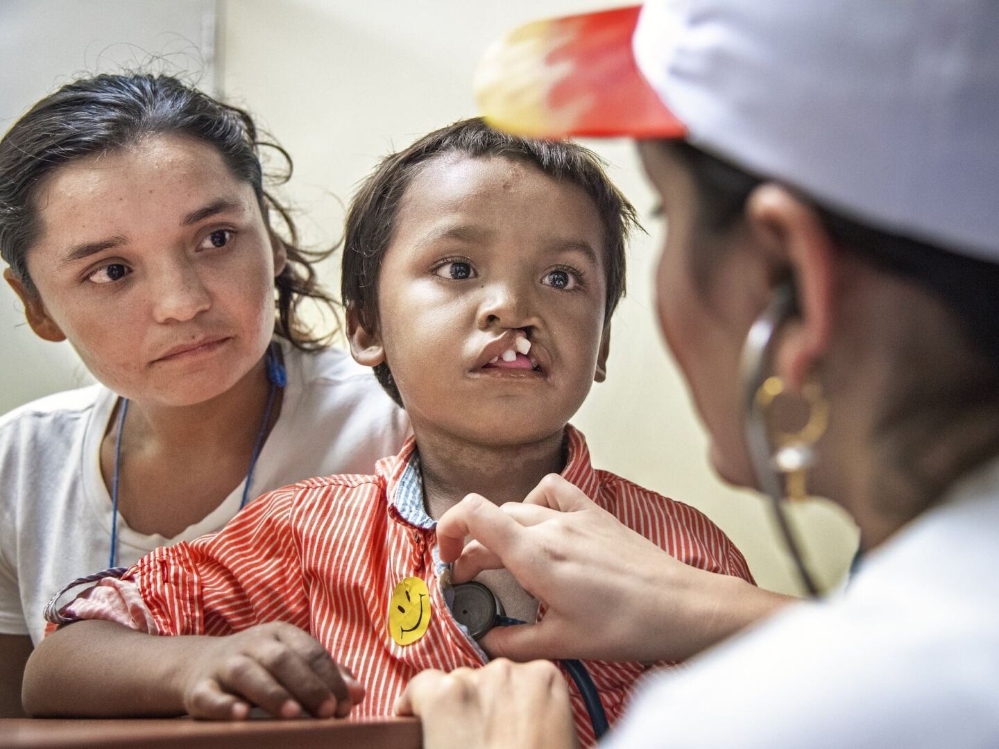 Pedro sits with his mom while being examined by an Operation Smile volunteer.