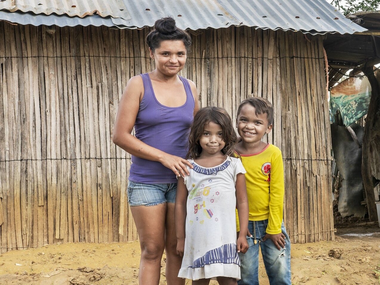 Pedro stands with his family in front of his home in Colombia.