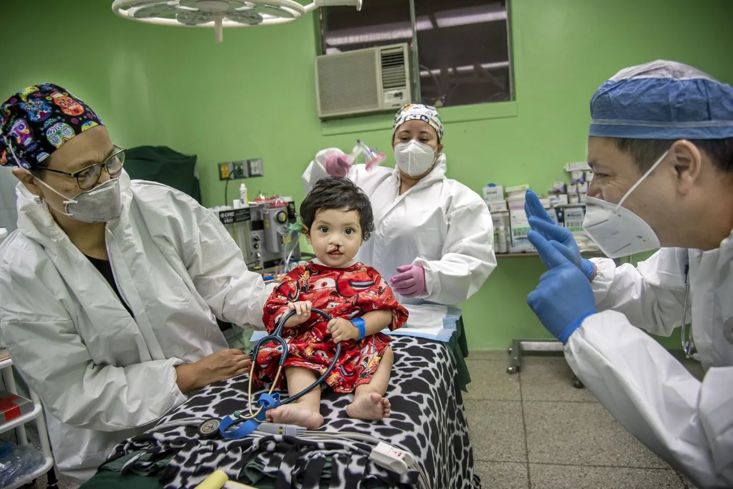 Operation Smile volunteers take a moment before surgery to let a patient play with the stethoscope.