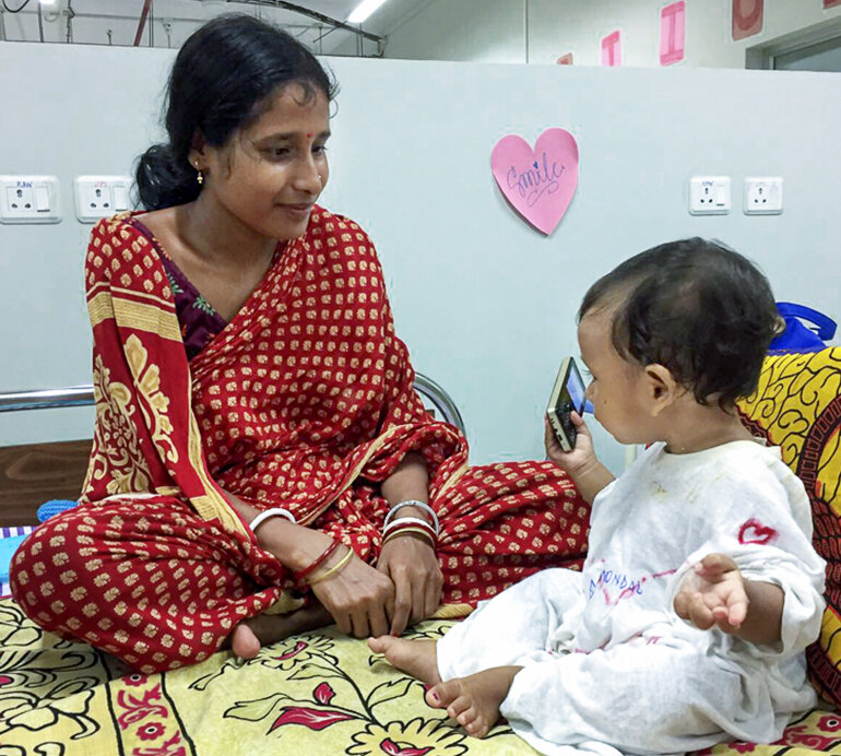 A 10-month-old patient dances as music plays from his mother’s phone shortly after receiving cleft lip surgery at the Future of Smiles surgical program.