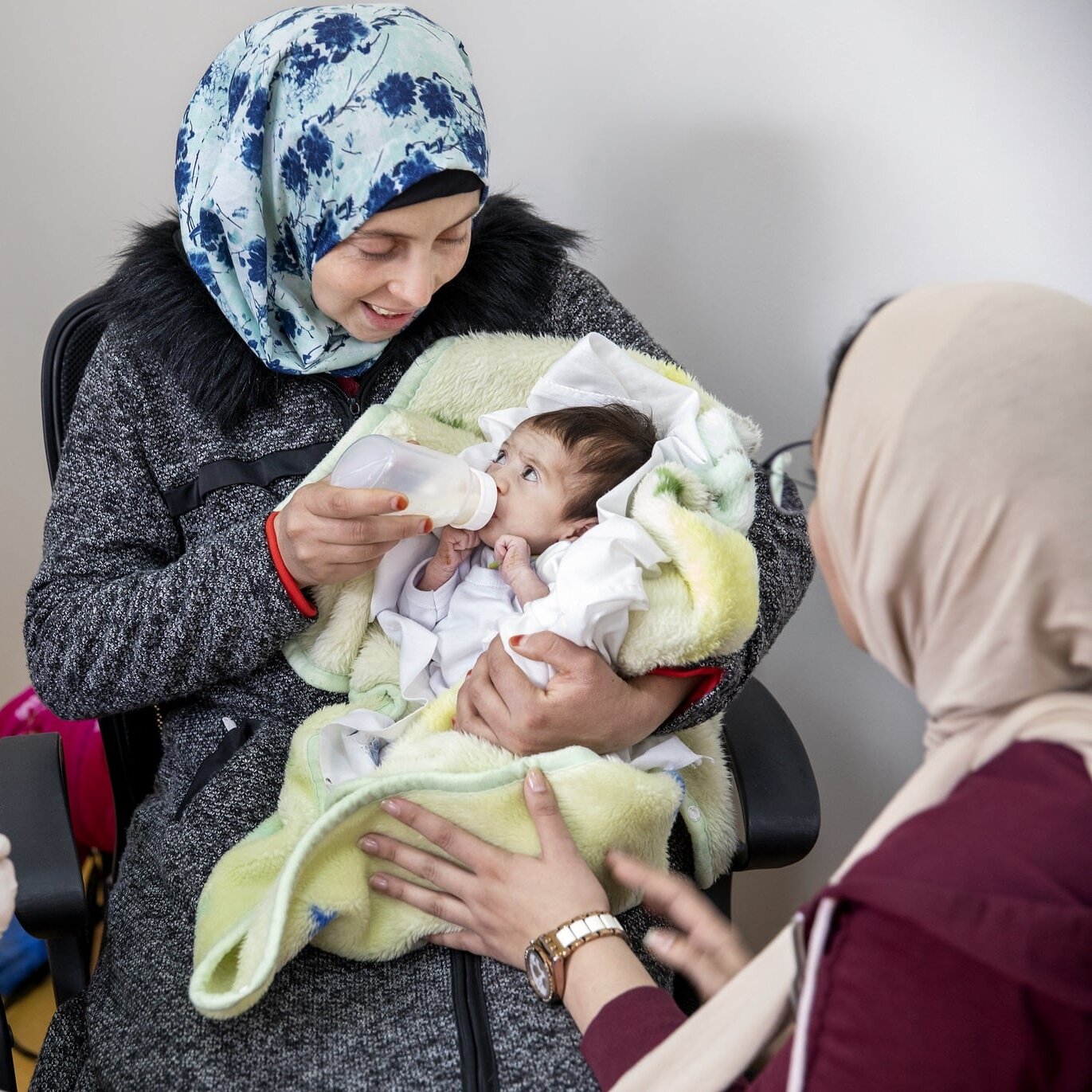 Volunteer dentist Dr. Teresita Pannaci of Venezuela, left, observes as Janat is fed by her mom while testing out her new feeding plate.