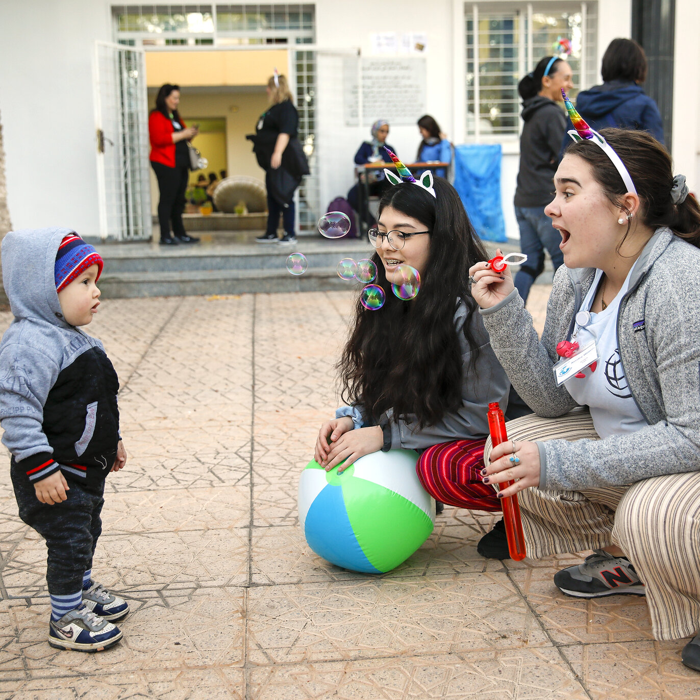 Students Ainsley Wuerth and Luzmia Lopez play with a patient’s sibling on the first day of screening for the Women in Medicine surgical program.