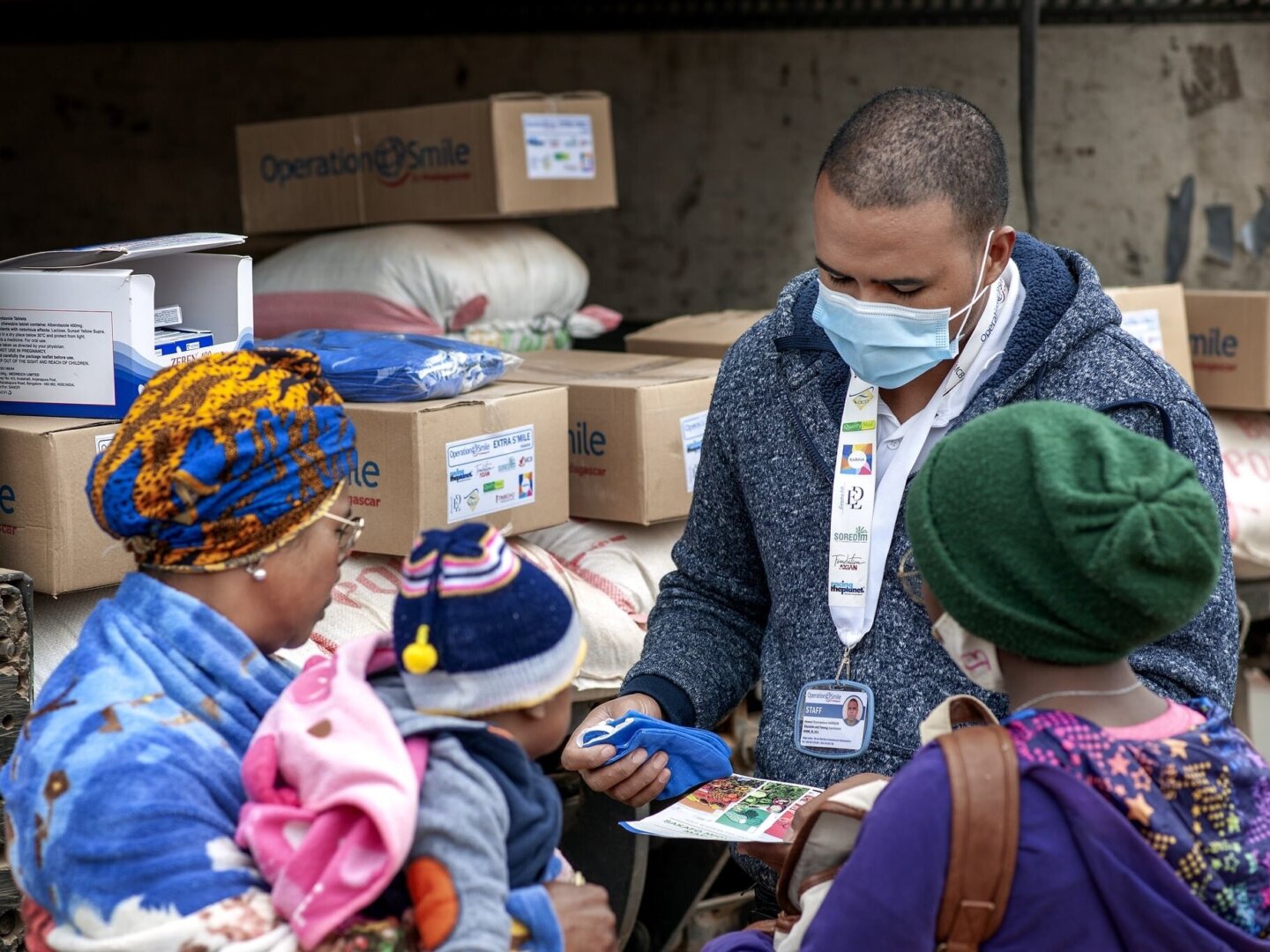 An Operation Smile volunteer provides information and supplies to a patient's family as part of nutrition program.