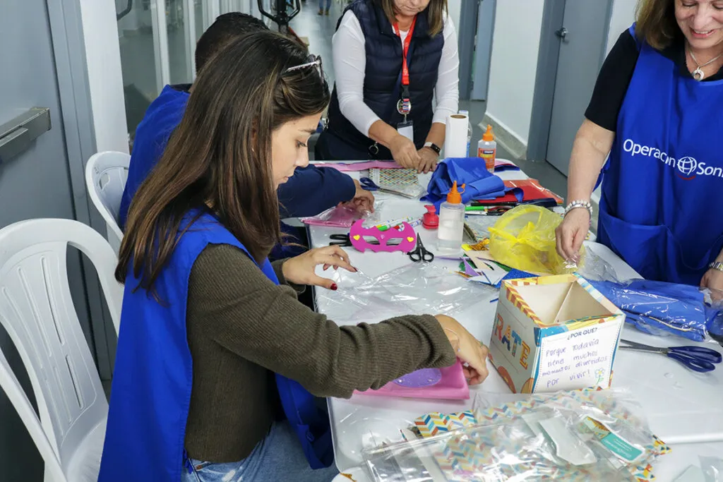 Corporate volunteers create superhero capes for children.
