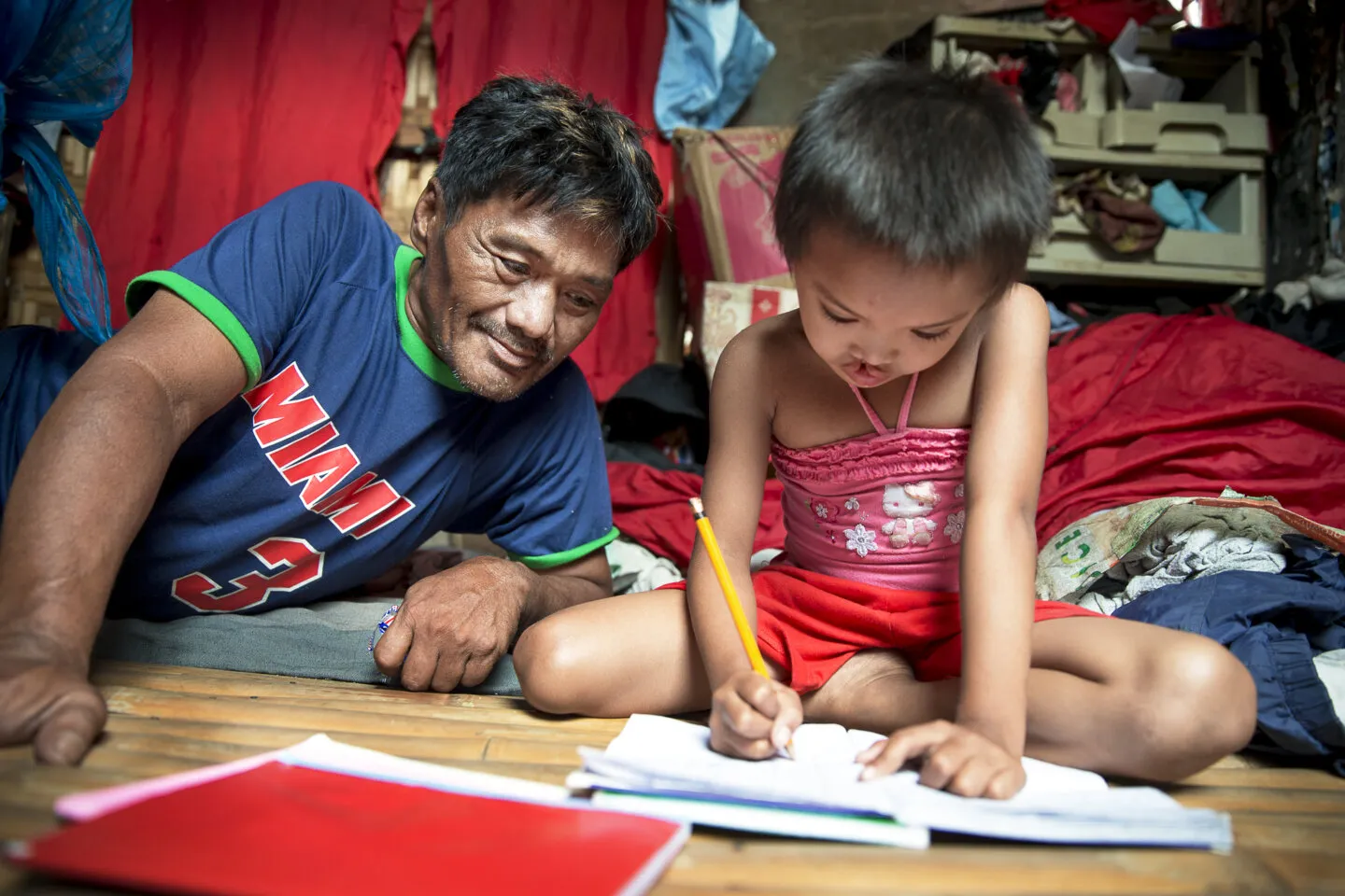 Jane Rose's father, Eutigio, watches as his daughter completes her homework.