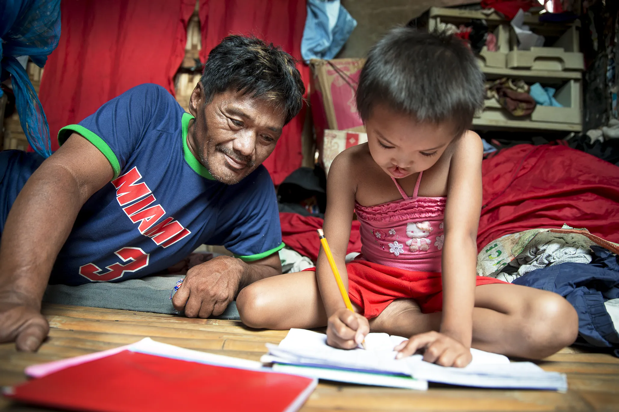 Jane Rose's father, Eutigio, watches as his daughter completes her homework.