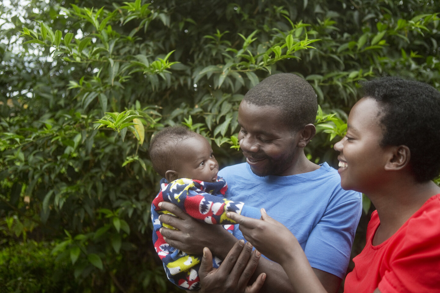Enok and his wife smile widely at their child.