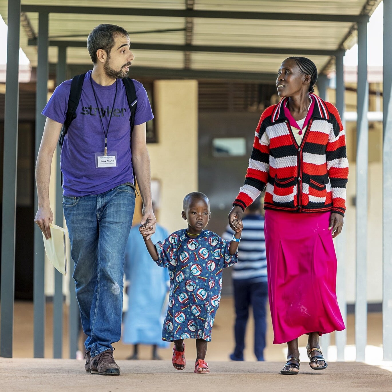 A representative of Stryker speaks with a patient and his family during a surgical program in Rwinkwavu, Rwanda.