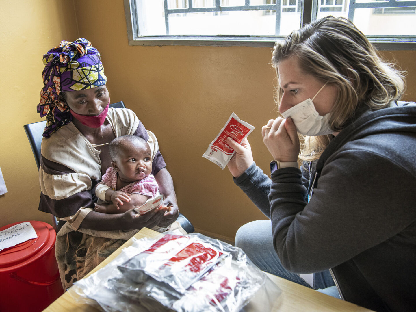 Operation Smile Staff Member Charlotte Steppling discussed nutrition and RUTF with a patient and their mother in Bushenge, Rwanda.