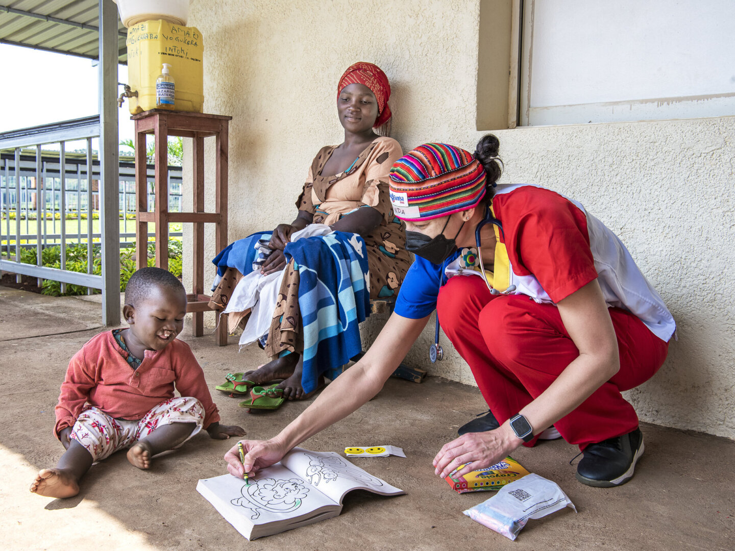 Nurse Linda James colors with Aime during a surgical program in Rwanda.
