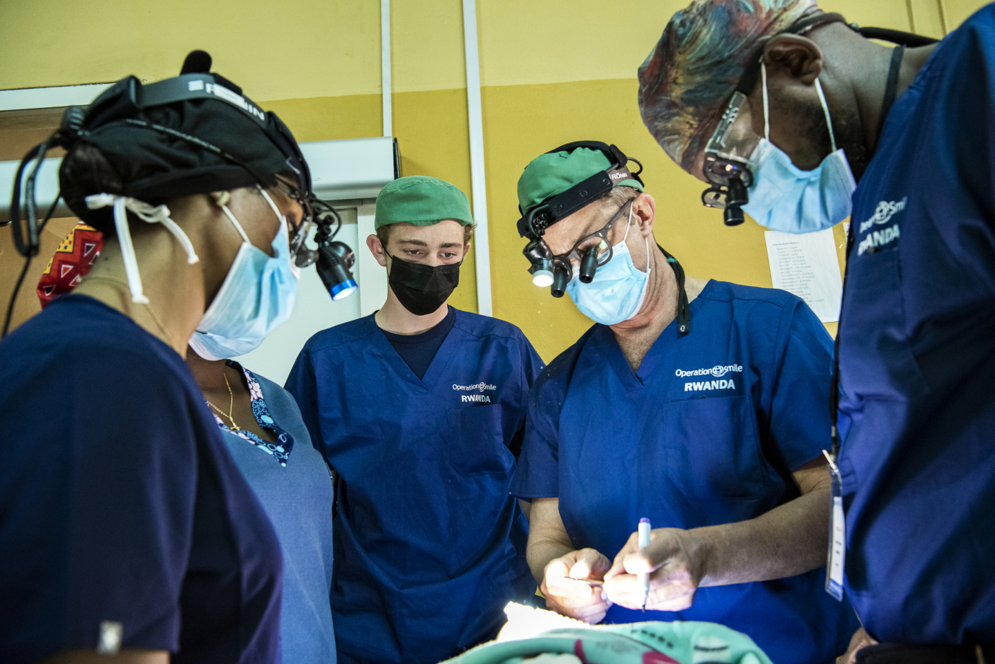 Through training and education opportunities, Operation Smile Rwanda has devoted years to enhancing the capacity of surgical care in the country with its surgical training rotations. Prior to surgery during the 2022 Rwanda surgical program, Liam Magee, center, watches as his father, Billy, demonstrates a surgical technique to plastic surgery resident Dr. Yves Nezerwa of Rwanda, right.