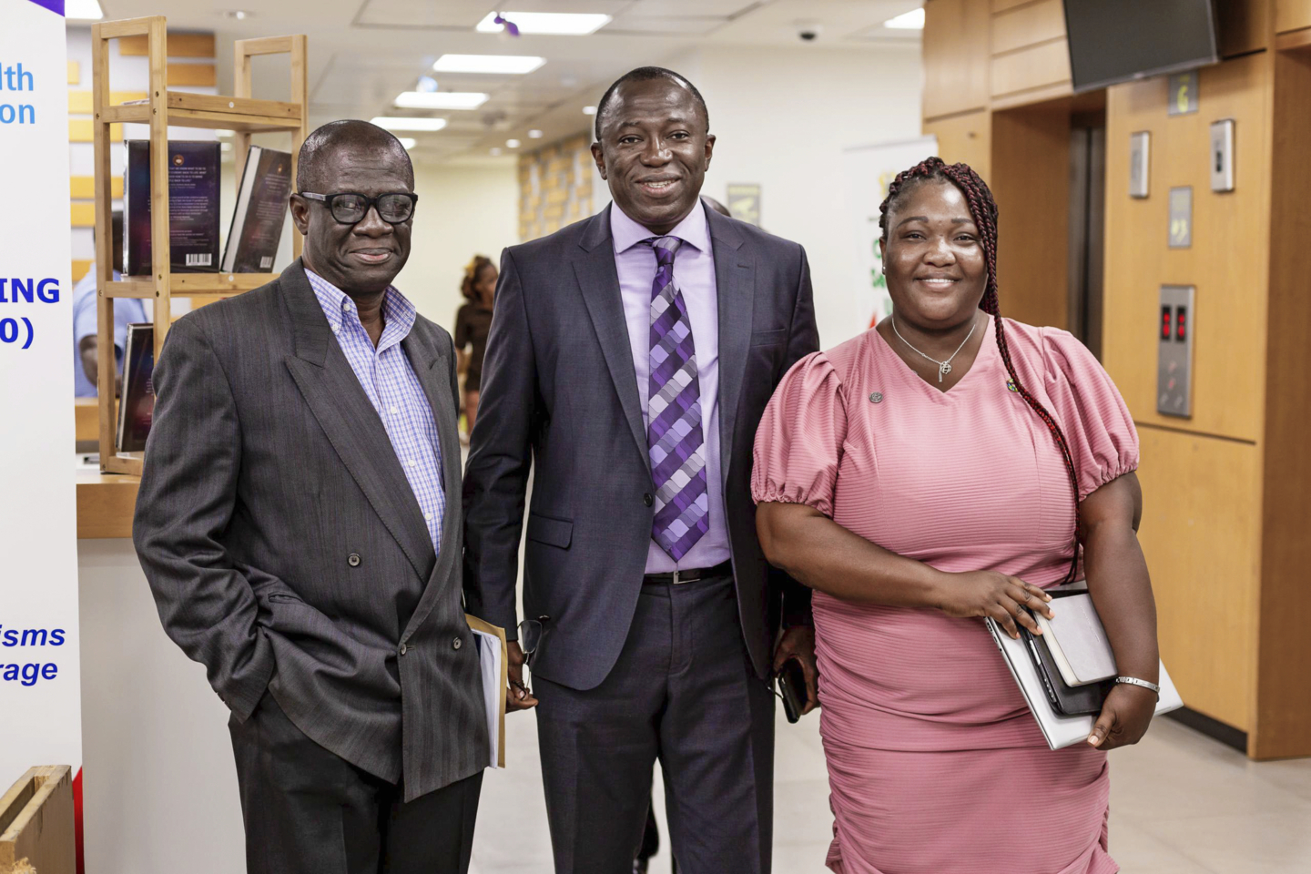 Three individuals smile for the camera while working on the Ghanian National Surgical, Obstetric and Anaesthesia Plan.