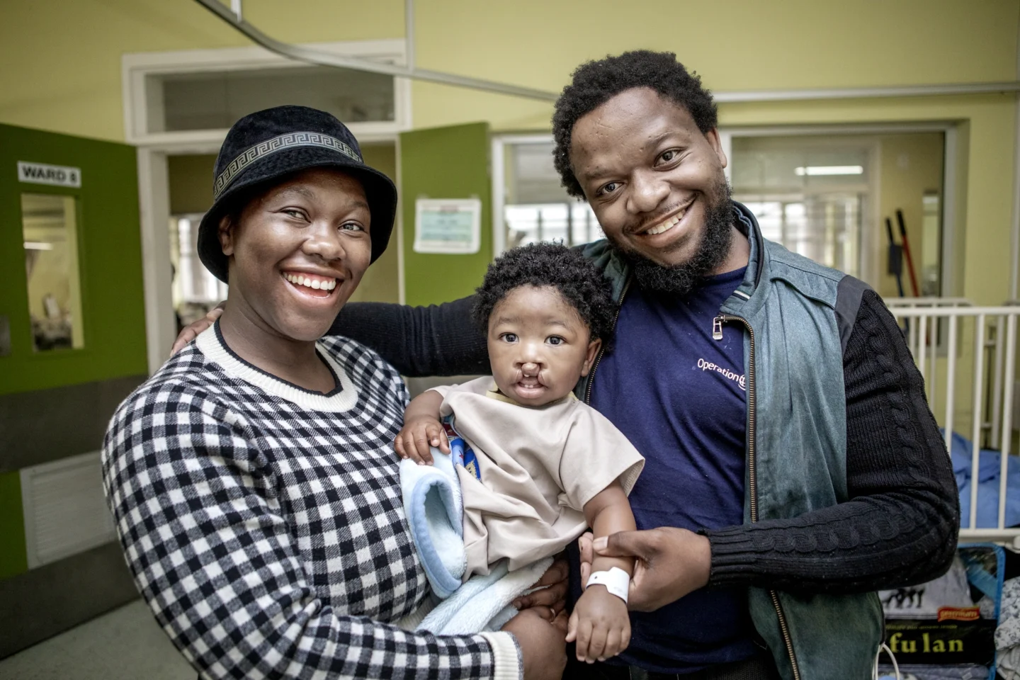 Nzulu and his parents smile for the camera during a surgical program.