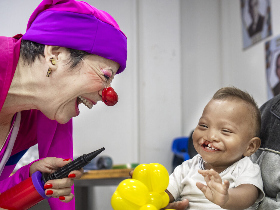 Ihan laughs while playing with a member of Clowns without Borders.