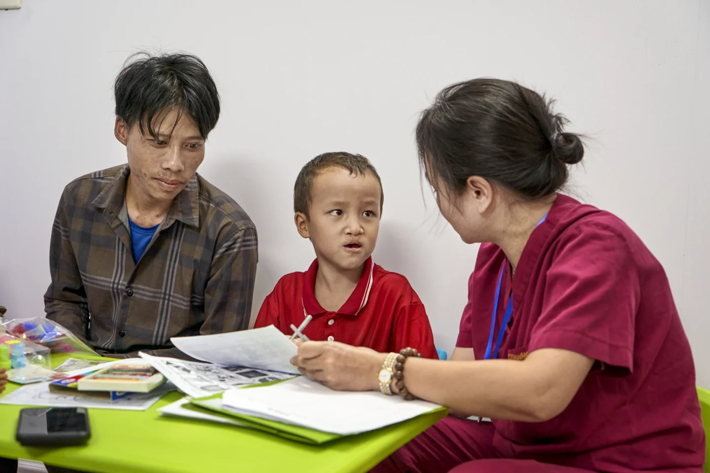 Vien and his father sit with a health care provider for speech therapy.