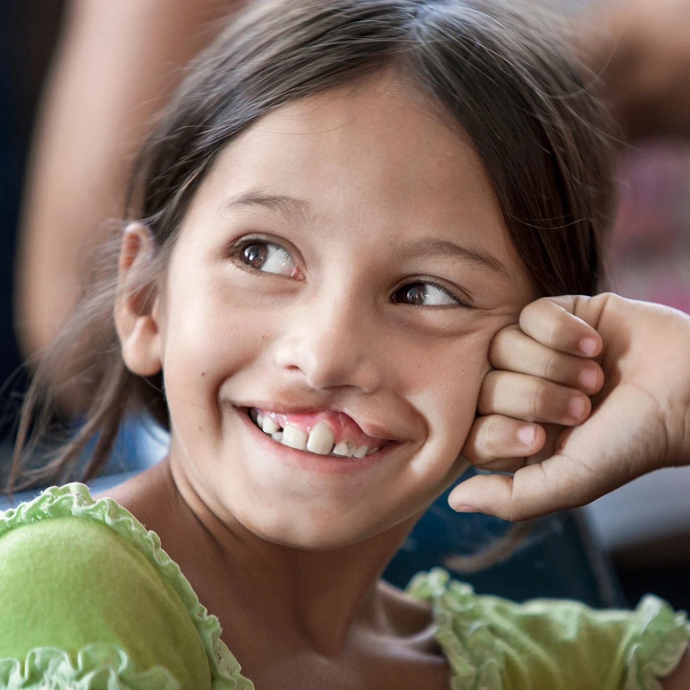 In a green shirt and resting her face on her handle, Antonia smiles.