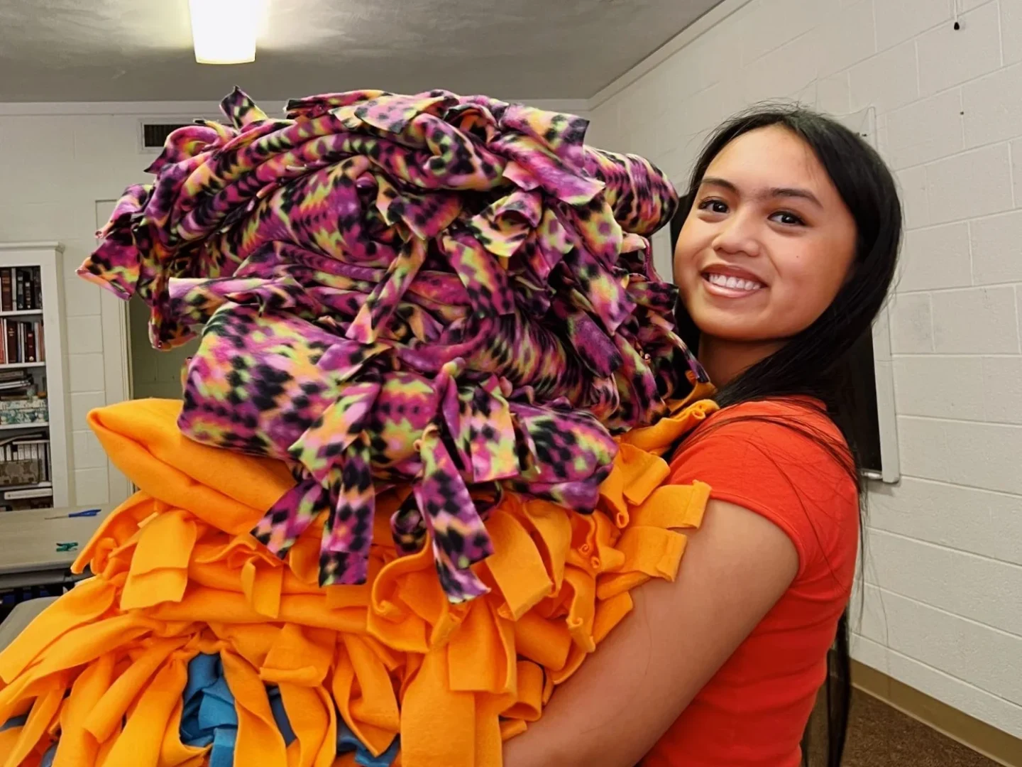 A camper holds blankets made for our patients.