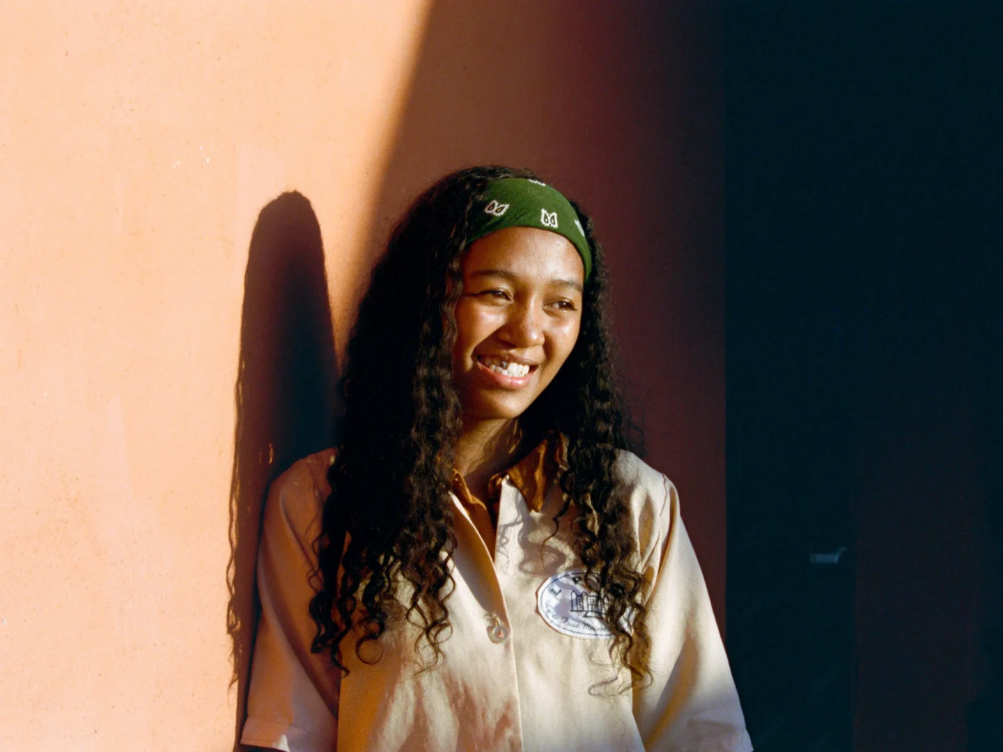 Narya leans against a wall, smiling for the camera.