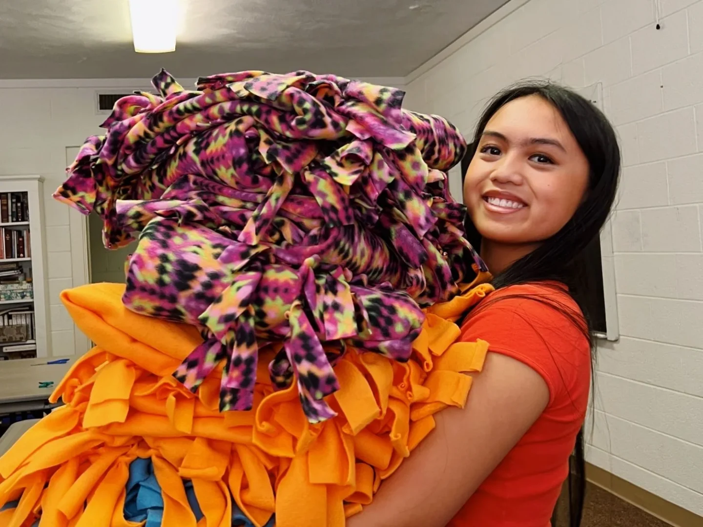 A camper holds blankets made for our patients.