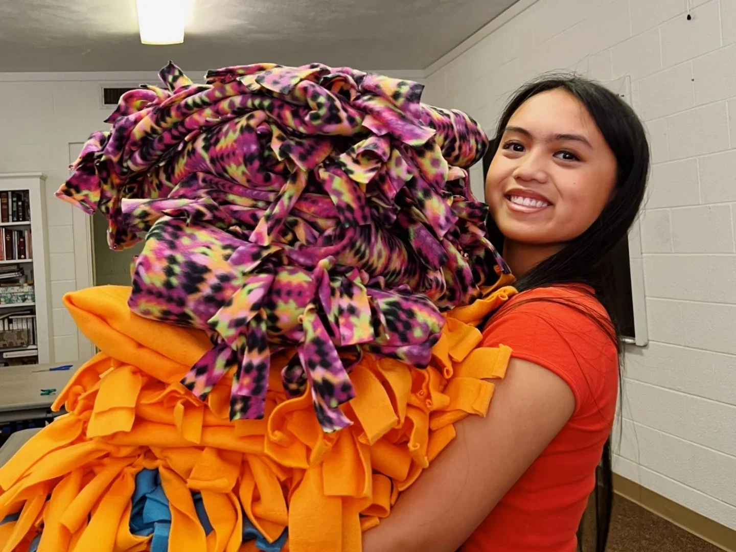 A camper holds blankets made for our patients.