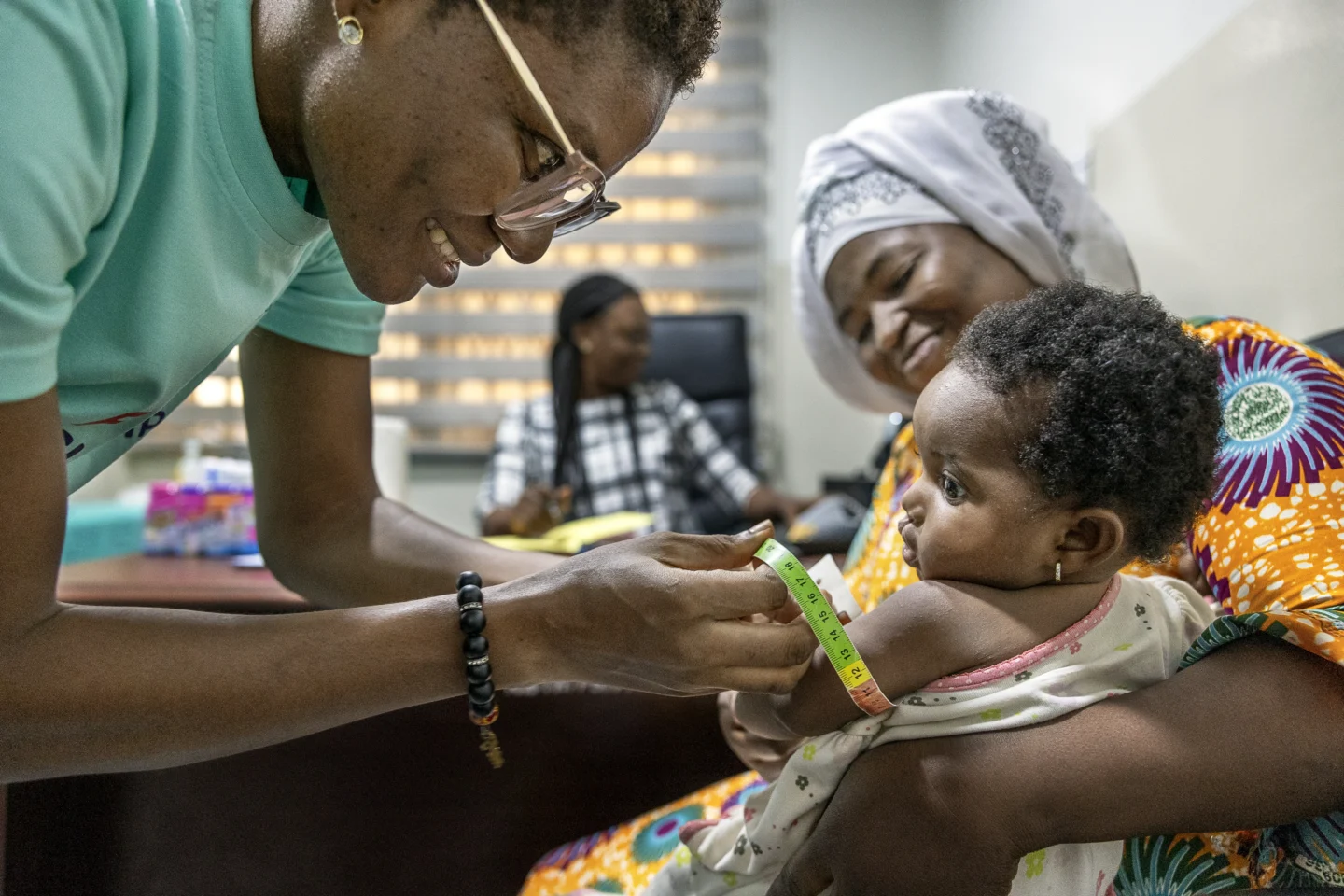 Alimatu holds Farida while a volunteer nutritionist from Ghana performs an assessment to determine if she is able to receive surgery.